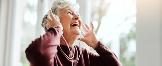 Senior woman listening to music through headphones in a peaceful memory care setting - Impact of Music Therapy
