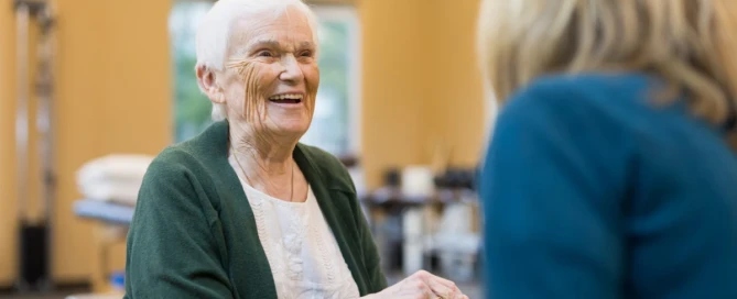 A memory care resident and team member share a moment during an activity at Farmington Square in Medford, OR.