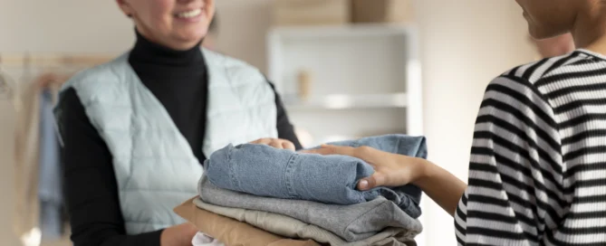 Senior and caregiver folding laundry together at Farmington Square Medford a senior care community