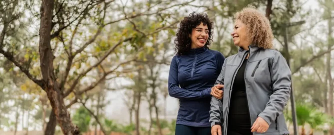 Mother and daughter walking in park, discussing What are the four rs of dementia care.